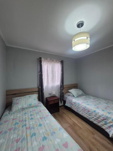 a bedroom with two beds and a light at Casa bosque arenal in Pucón