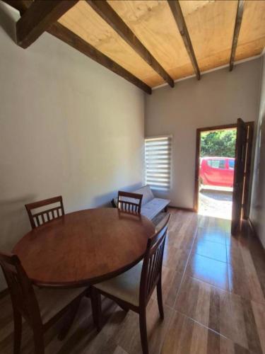 a dining room with a wooden table and chairs at Casa bosque arenal in Pucón