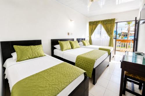two beds in a hotel room with a window at Alborada Hotel Melgar in Melgar