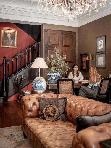 two people sitting at a table in a living room with a couch at M Maison Particulière Porto in Porto