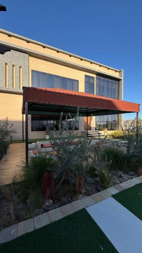 a building with a red awning next to a garden at Rawnaq aljabal chalet in Qurayyah