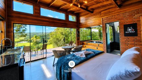 a bedroom with a bed and a large window at Cabana Bad Wolf - Rancho Queimado - SC in Rancho Queimado