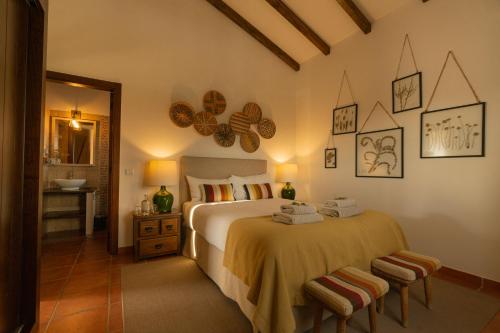 ein Schlafzimmer mit einem großen Bett und zwei Hockern in der Unterkunft Monte do Alento - Castro da Cola in Alcaria