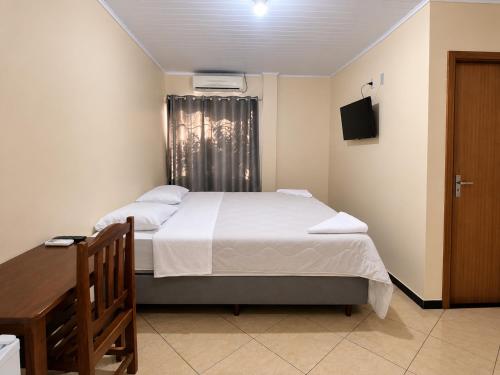 a bedroom with a bed and a desk and a window at hotel Maanaim in Candói