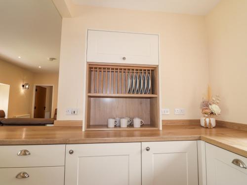 a kitchen with white cabinets and wooden counter tops at Millmoss Cottage in Turriff
