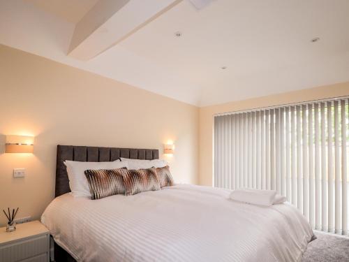 a bedroom with a large white bed with a window at Millmoss Cottage in Turriff