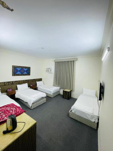 a hotel room with three beds and a television at فندق دار العوالي3 in Medina