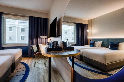 a hotel room with two beds and a table at voco Gent by IHG in Ghent