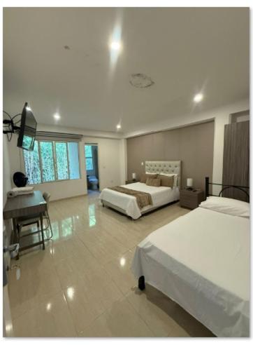 a large room with two beds and a desk and a desk at HOTEL ROMA VIp in Pereira