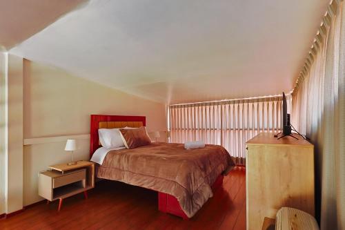 a bedroom with a bed and a table with a lamp at Sumaq Sisa Home & Loft in Cusco