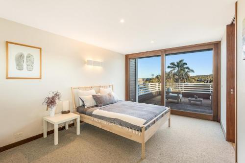 a bedroom with a bed and a large window at East Lane in Tathra