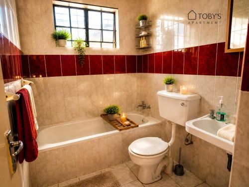 a bathroom with a toilet and a tub and a sink at Toby's Apartment in Mbabane