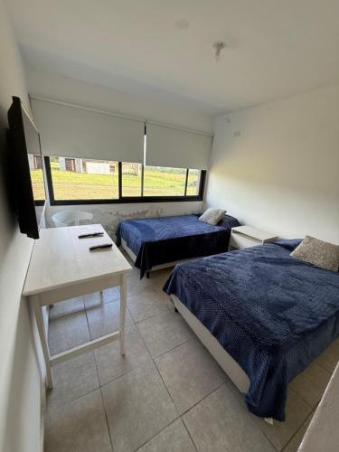 a room with two beds and a desk and a tv at Casa Marti in Los Reartes