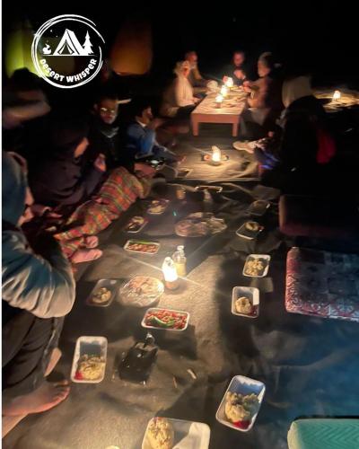a group of people sitting around a table with plates of food at مخيم همسات الصحراء in Siwa