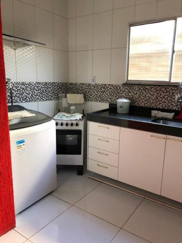 a kitchen with a stove and a white refrigerator at Refúgio em Jacumã Conforto, Tranquilidade e Praia in Conde