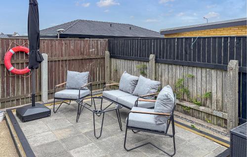 a patio with three chairs and an umbrella on a fence at Awesome Home In Thyborøn With Wifi in Thyborøn