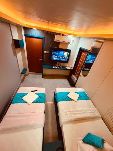 a small room with two beds and a flat screen tv at Guru hotel and lodge in Itahari