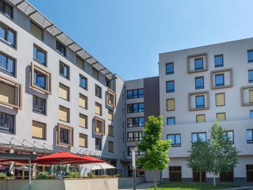 an apartment building with a cafe in front of it at Adagio Access Grenoble Université in Saint-Martin-dʼHères