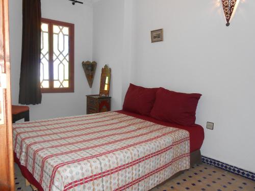 a bedroom with a bed with red pillows and a window at Petit Bijou de Tanger in Tangier