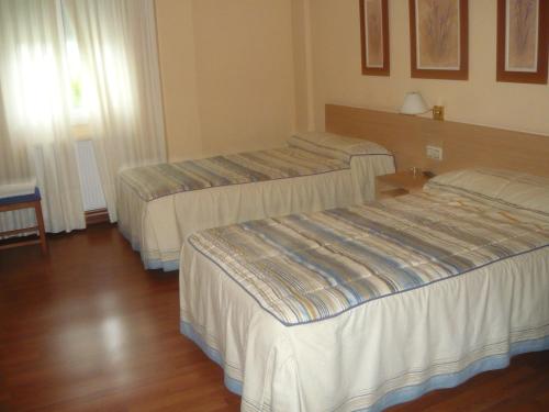 two beds in a hotel room with wooden floors at Pensión HK in A Angueira de Suso