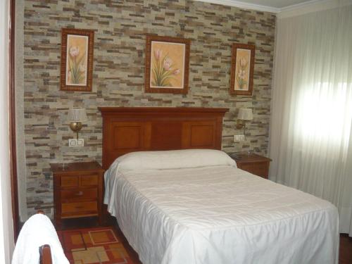 - une chambre avec un lit et un mur en briques dans l'établissement Pensión HK, à A Angueira de Suso