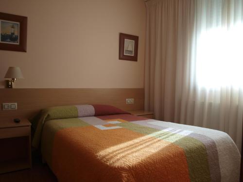 a hotel room with a bed and a window at Pensión HK in A Angueira de Suso