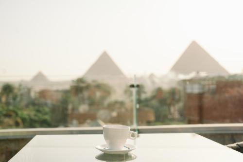 a coffee cup sitting on a table in front of a window at Irit pyramids inn in Cairo