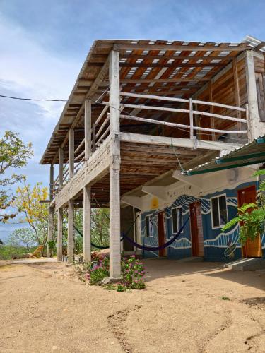 ein Haus mit einem Holzdach und Blumen davor in der Unterkunft El Cielo Hostel in Barra de la Cruz