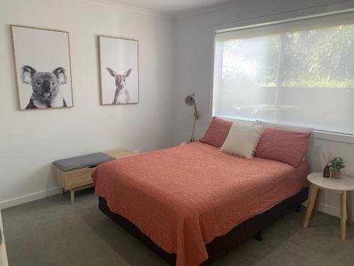 a bedroom with a bed and a window with two dogs on the wall at Kuruwa in Tathra