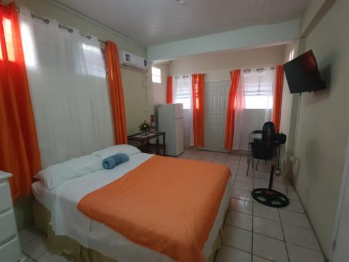 a bedroom with a bed with an orange blanket at Hilltop View Guesthouse in Castries