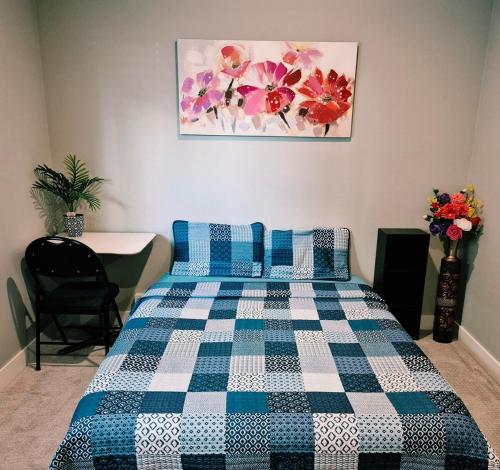 a bedroom with a bed with a blue and white checkered blanket at Spacious Private Suite Minutes Away from Ocean,Trails and Stores in Langford