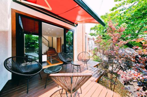a deck with chairs and tables and an umbrella at Danro no Yado Concept House Hoshida in Katano