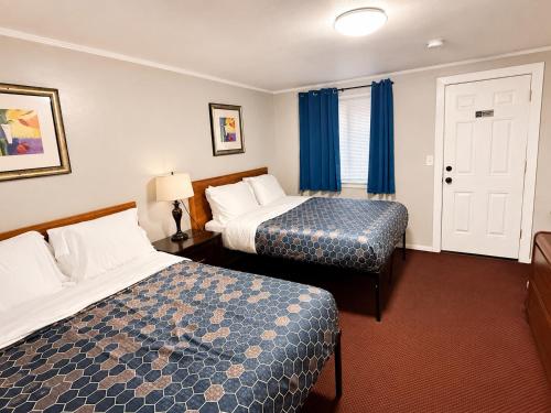 a hotel room with two beds and blue curtains at Beachway Motel in Salisbury