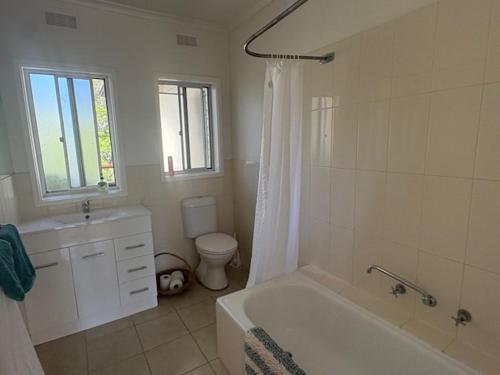 a bathroom with a tub and a sink and a toilet at Cliff Place in Tathra