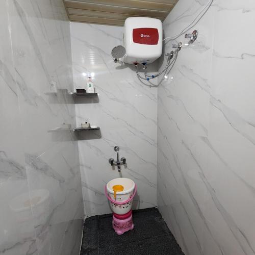 a bathroom with a toilet in a white tiled wall at Sattva Farmstay in Bangalore