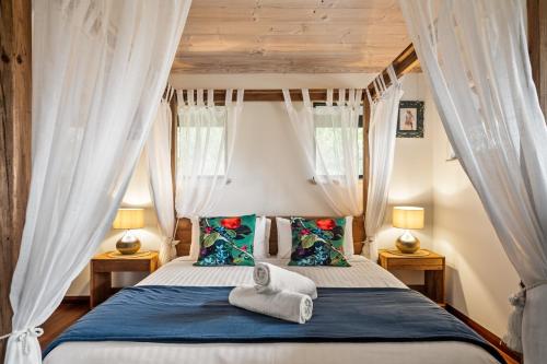 a bedroom with a bed with curtains and towels on it at Riveresque - Spa Bath - Forest Views in Margaret River Town