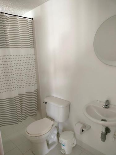 a white bathroom with a toilet and a sink at Oasis Santafe in Santa Fe de Antioquia
