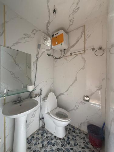 a white bathroom with a toilet and a sink at Lũng Cú H'Mông Homestay in Loung Co