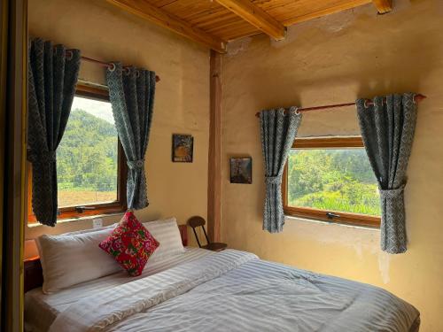 a bedroom with a bed and two windows at Lũng Cú H'Mông Homestay in Loung Co