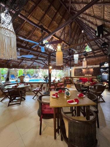 a restaurant with tables and chairs and a pool at Cocos Cabañas Playa del Carmen Adults Only in Playa del Carmen