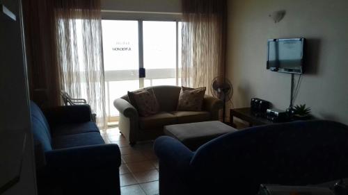 a living room with a couch and a tv at Stella Maris Apartment 132 in Amanzimtoti