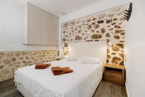 a bedroom with a white bed with two towels on it at Lithos Blue Agios Vasilios in Áyios Vasílios
