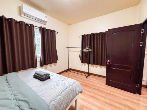 a bedroom with a bed and a black door at Honey Home Pai in Pai