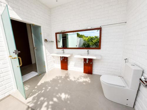 a bathroom with a toilet and two sinks and a mirror at Dutch Bay Resort & Spa in Kalpitiya