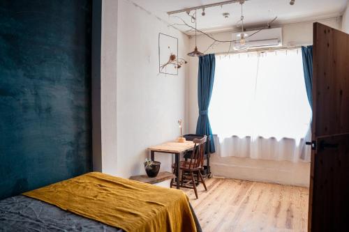 a bedroom with a bed and a table and a window at 暮らす実験室 in Taketa