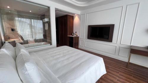 a bedroom with a white bed and a flat screen tv at Khác Sạn Oytes Bay in Xa Thang Nhi