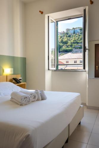 a bedroom with a white bed and a large window at Hotel Miramare in Pietra Ligure