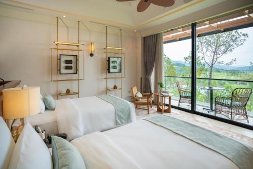 a hotel room with two beds and a large window at Silk Path Dong Trieu Golf Course & Villas in Trại Sưu