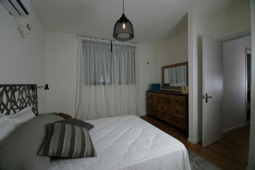 a bedroom with a bed and a dresser and a mirror at Cozy modern apartment in Hadera in H̱adera