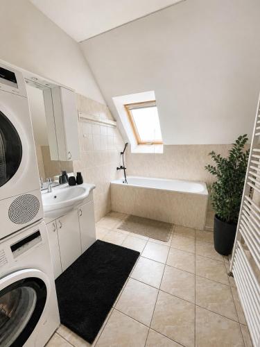 a bathroom with a tub and a sink and a washing machine at Veľký rodinný apartmán s výhľadom na zeleň a hory v centre Piešťan s parkovaním in Piešťany